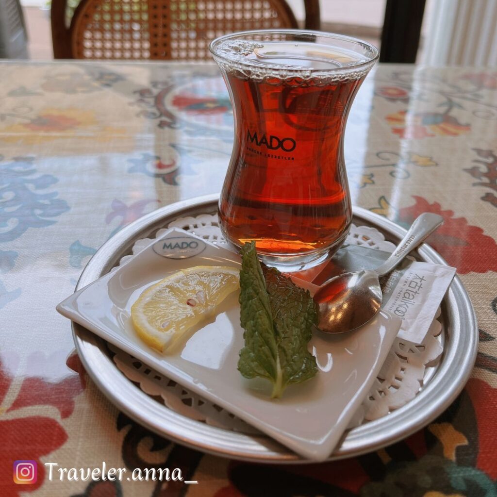 a glass of tea with lemon and leaf on a plate